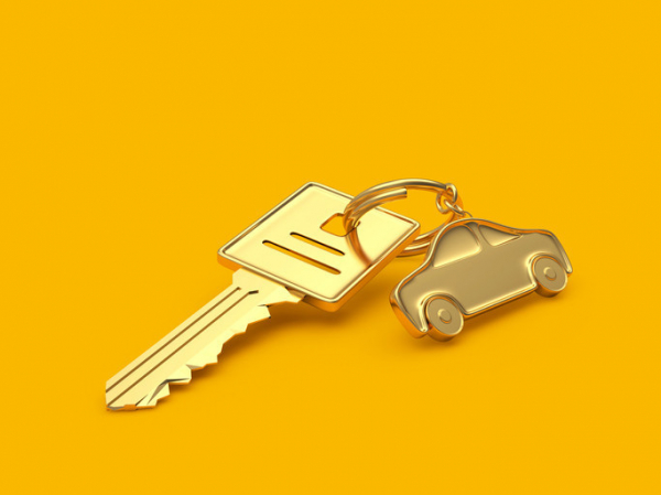 photo of a square-topped gold car key and a gold car on a key ring against a deep yellow background